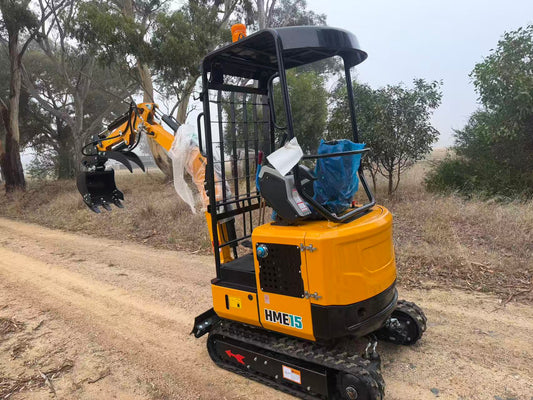 HandyMax HME15 mini excavator with bucket and grapple attachment parked on rural dirt track