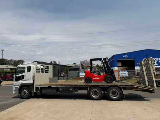 Handymax HMF25-D30 2.5-tonne diesel forklift loaded on delivery truck - red industrial forklift for warehouses and material handling