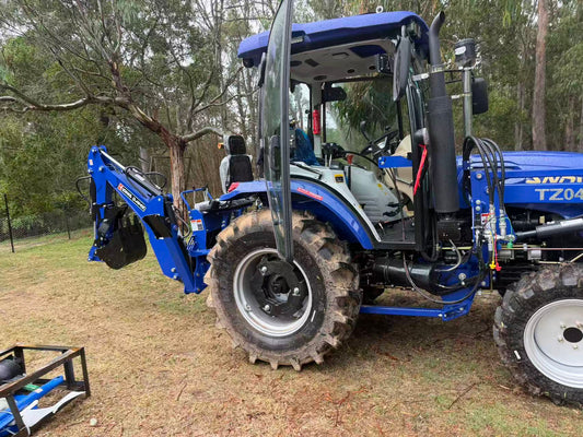 HandyMax HT45C blue tractor with rear backhoe attachment on rural property
